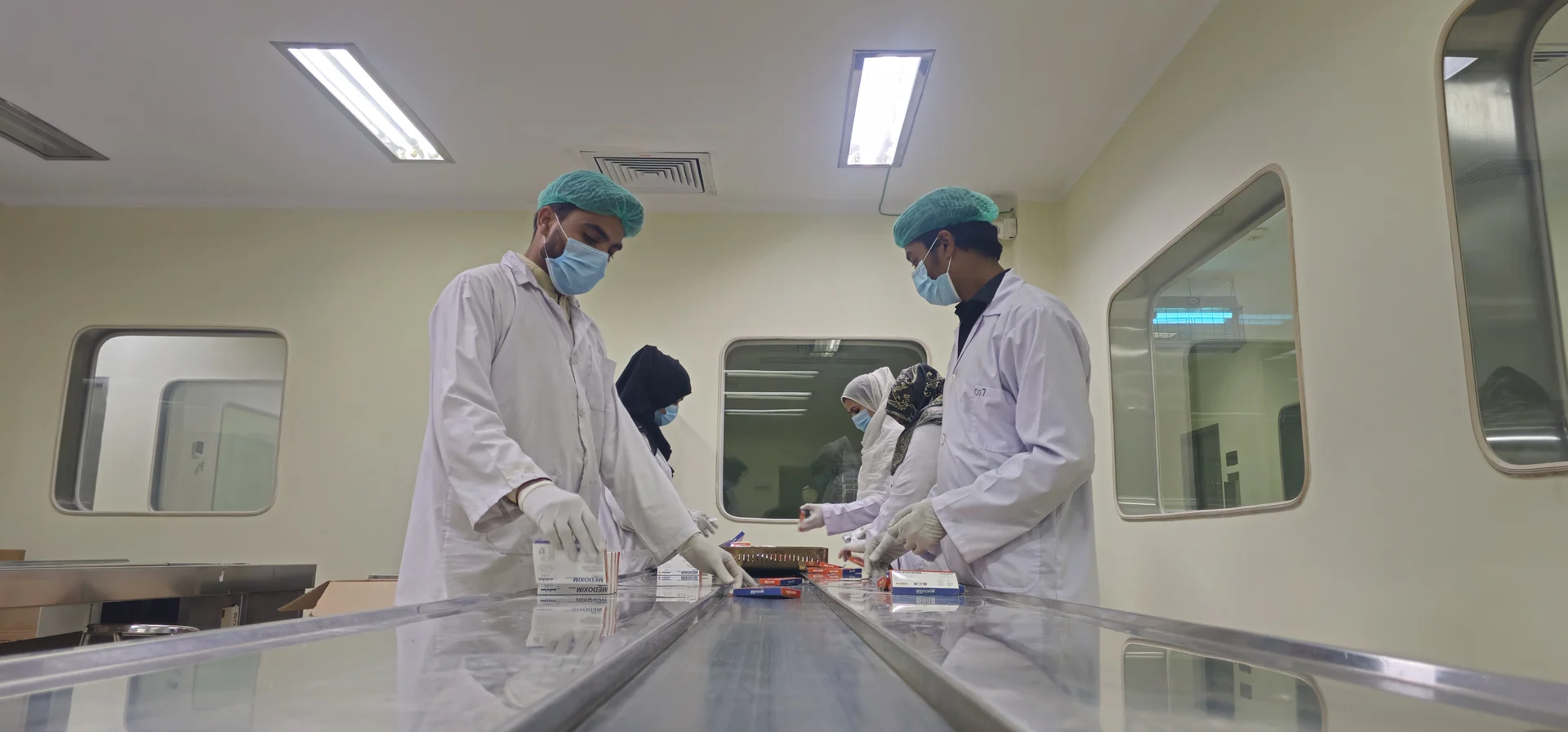 HiMedic personnel in protective gowns working on a pharmaceutical packaging line